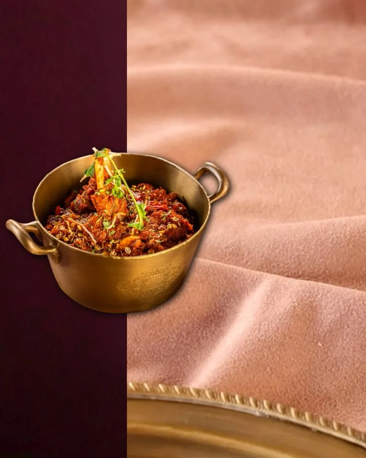 A brass kadhai of rich red frontier curry.